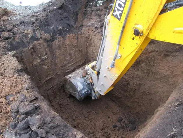Экскаватор копает яму под колодец
