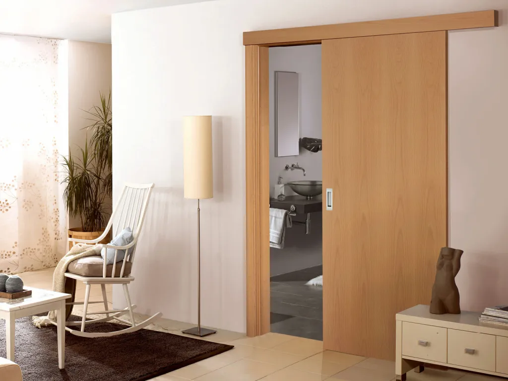 Дверь-купе теплого светлого оттенка с древесной фактурой между гостиной и ванной комнатой